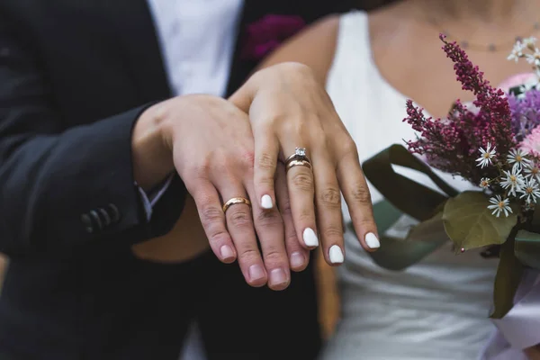 Bride and groom showing wedding rings on their fingers close up. High quality photo