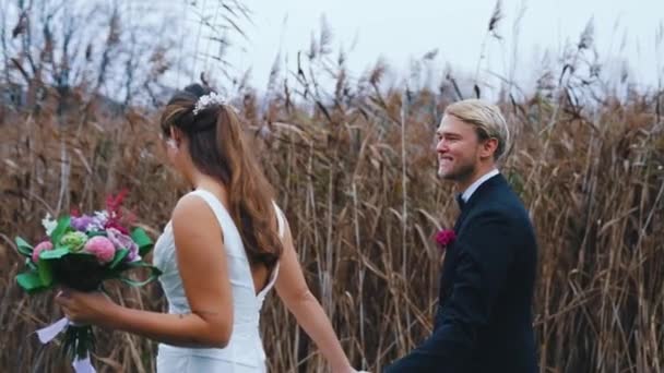 晩秋の素敵な屋外結婚式 背景のブロンドの北欧の夫を見て前景では認識できない長い髪の毛の毛がぼやけている 楽しさと笑い 高品質4K映像 — ストック動画