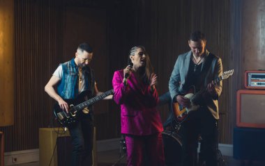 Gitarlarda ona eşlik eden müzisyenlerle tek başına şarkı söyleyen bir kadın. Yüksek kalite fotoğraf