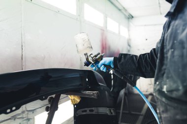 Beyaz sprey kabinin içi. Otomobil boyama işlemi. Araba çamurluğu cilalıyor. Koruyucu tulumlu, boya sprey tabancası kullanan tanınmayan biri. Yüksek kalite fotoğraf