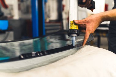 Araçlar ve makine konsepti. Araba penceresi kurulumu. Kafkas el tutkalı tabanca tutarken ve arka pencerenin yüzeyine siyah yapıştırıcı sürerken yakın plan portresi. Yüksek kalite fotoğraf