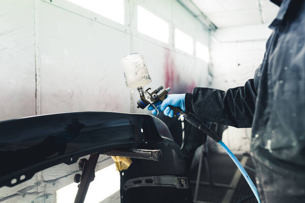 Интерьер белого баллончика. Процесс автомобильной живописи. Лак для крыльев автомобиля. Неузнаваемый человек в защитном комбинезоне с помощью лакокрасочного пистолета. Высокое качество фото