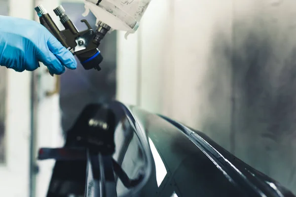 汽车翻新和详细过程 用一只手拿着防护手套的喷雾枪 在喷漆间对汽车部件进行清漆的特写透视 高质量的照片 — 图库照片