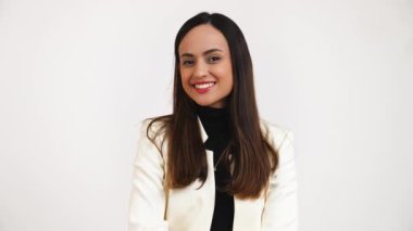 Genç, esmer, gülümseyen bir kadın, beyaz arka planda soyutlanmış bir şekilde yan tarafa bakıyor. Yüksek kalite 4k görüntü