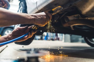 Mavi yakalı işçi konsepti. Açı öğütücü kullanımda. Tehlikeli ısı parıldıyor. Kafkasyalı bir tamircinin iki eli. İç mekan alçak açı. Yüksek kalite fotoğraf