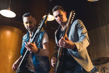 İki genç gitaristin müzik konseptiyle birlikte bir stüdyoda performans sergilediği orta boy bir çekim. Yüksek kalite fotoğraf