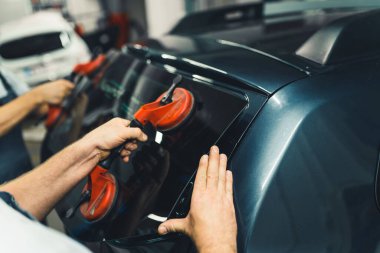 Ön cam ve arka cam tamiri seti için cam vakumlama bardakları gereklidir. Siyah arabanın arka camını indiren tanınmayan iki beyaz tamircinin elleri. Yüksek kalite fotoğraf