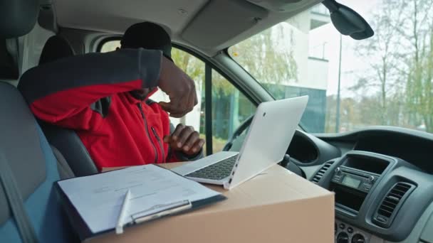 흑인젊은 배달부가 운전석에 서류를 작성하고 노트북 컴퓨터로 일하고 고품질 — 비디오