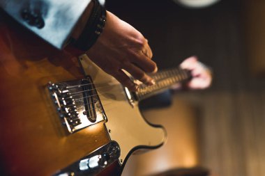 Elektro gitarın yakın çekimi. Elektro gitar kullanan tanınmayan beyaz adamın elleri. Kapalı çekim. Arka plan bulanık. Yüksek kalite fotoğraf