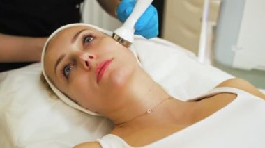 En sevdiği SPA salonunda mikro dermabrüksiyon işlemi sırasında 30 'lu yaşlarında güzel beyaz bir kadın. Siyah üniformalı tanınmayan profesyonel kozmetikçi. SPA iç mekan ve ekipman. Yüksek kalite 4k