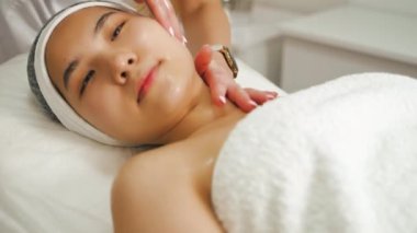 Profesyonel masaj terapisti tarafından yapılan geleneksel Japon yüz gerdirme masajı sırasında 20 'li yaşlarındaki güzel Asyalı kadın sırt üstü uzanıyor. Yüksek kalite 4k görüntü