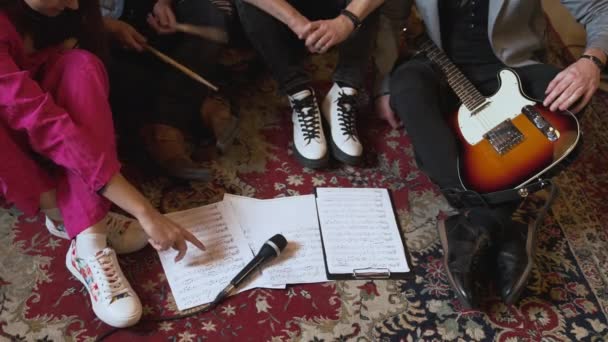 音楽バンドは新しい曲を学び ノートと一緒に床に座っています 顔も見えない 高品質4K映像 — ストック動画