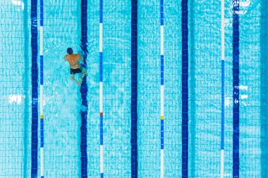 Yüzme havuzunda tek başına yüzen bir adamın kuş bakışı görüntüsü. Yüksek kalite fotoğraf