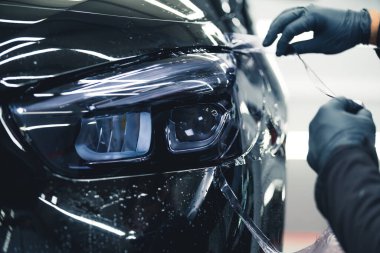 Otomatik lambalar kararıyor. İki el koruyucu eldiven giyip arabanın ön ışıklarına renk katıyor. - Evet. Yüksek kalite fotoğraf