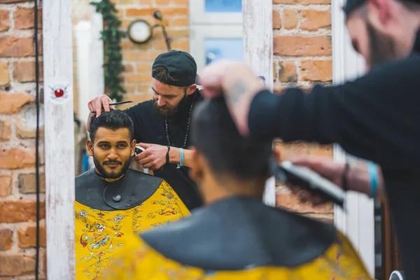 bearded hairdresser making a haircut for his permanent customer, medium shot man beauty and self-care concept. High quality photo