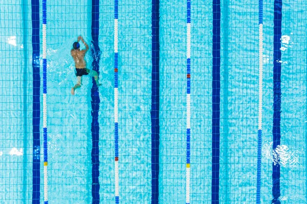 Active leisure time concept. Unrecognizable man in swimming alone in a swimming pool. High angle shot. High quality photo