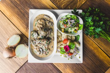 Beyaz tabakta servis edilen kalın mantar soslu leziz sığır filetosu ve patates köftesi ve salata. Beslenme konsepti. Yüksek kalite fotoğraf