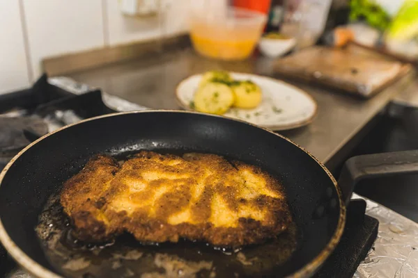 Polish cuisine concept. Frying process of pork chop cutlet. Piece of meat on a frying pan with grease. Indoor portrait. High quality photo