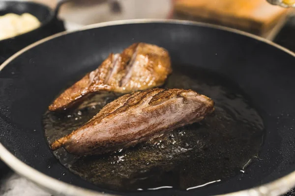 Duck fillet on frying pan. Meat dish from Polish cuisine concept. Two pieces of duck fillet frying in oil. Closeup shot. High quality photo