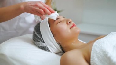 Termokaldırma işleminden sonra Asyalı bir kadın için yüz masajı yapan bir profesyonel. Orta boy güzellik kliniği. Yüksek kalite 4k görüntü