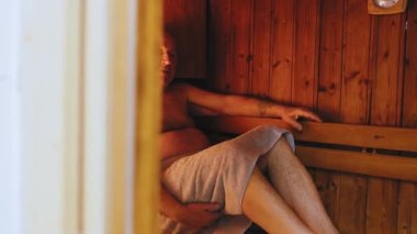 60 yaşın üzerindeki yaşlı adam saunada saunaya sarılıp saunada terliyor. Yüksek kalite 4k görüntü