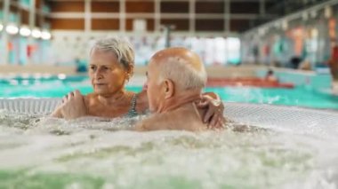 Yaşlı, emekli bir adam ve kadın, kabarcıklı spa jakuzisinde dinleniyorlar. Yüksek kalite 4k görüntü