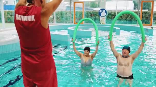 老年人在游泳池里和教练一起用面条锻炼 高质量的4K镜头 — 图库视频影像