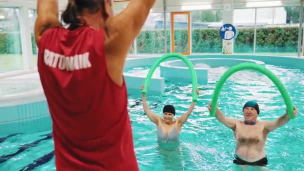 老年人在游泳池里用面条做完教练的练习后重复练习 高质量的4K镜头 — 图库视频影像