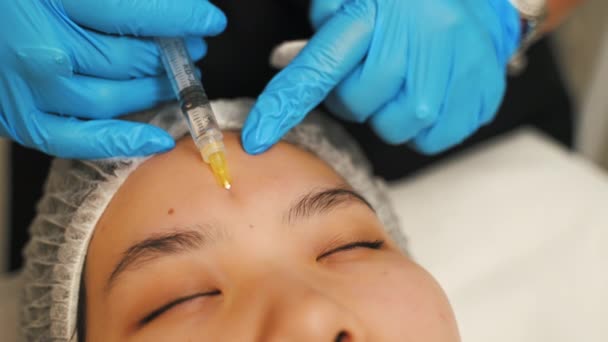 眉毛填充注射器的概念 专业专家戴着防护手套 在注射胶原蛋白时 将面带微笑的日本妇女置于Spa床上的室内肖像画 — 图库视频影像