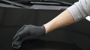 Profesyonel biri tarafından siyah araba kaputuna seramik kaplamanın yavaş uygulanması. Son derece yakın çekim. Yüksek kalite 4k görüntü