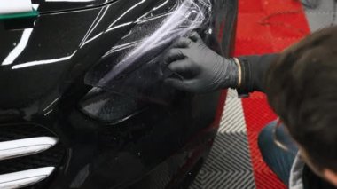 Profesyonel olarak kararmadan önce ön farları temizliyorum. Su belli bir mesafeden uygulanır. Bunu takan kişi siyah eldiven takıyor ve omuzlarını kapatıyor. Yüksek kalite 4k görüntü