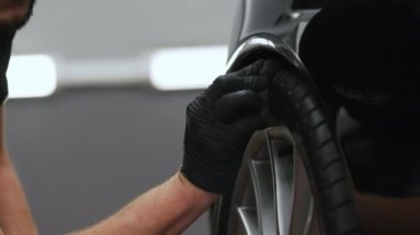 Siyah eldivenli biri siyah bir süngerle araba lastiğini yürütür. Ön plana odaklan. Arka plan bulanık. Yüksek kalite 4k görüntü