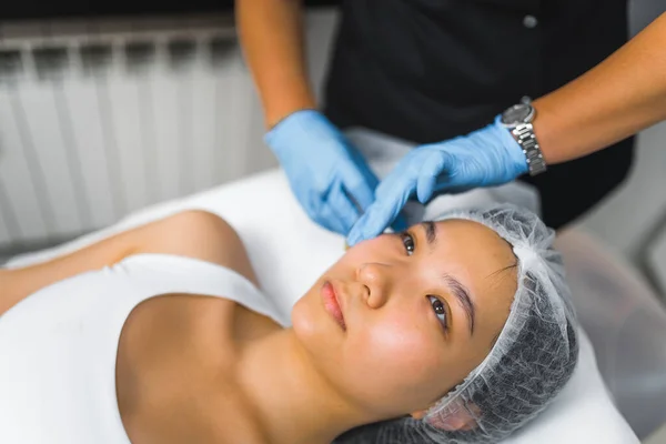 High angle shot of a woman laying down with her eyes open and receiving a collagen injection. Beauty treatment. Aesthetic medicine concept. Beauty concept. High quality photo