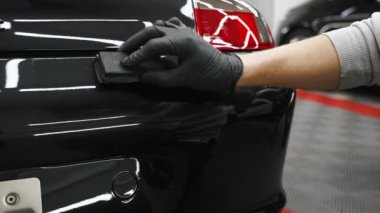 Bir uzman tarafından arabanın arka tarafına seramik kaplama uygulaması yavaş yavaş dikey hareket ettiriliyor. Yakın çekim. - Evet. Yüksek kalite 4k görüntü