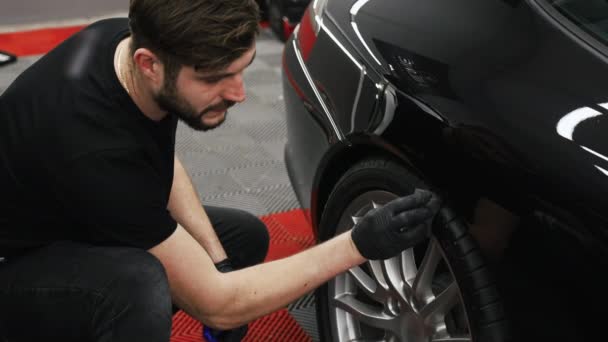 一个机修工穿着黑色T恤和黑色手套 使黑色汽车轮胎变黑 是的高质量的4K镜头 — 图库视频影像