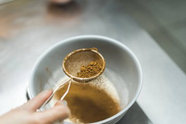 Bir fırıncının tarçın elleyip metal mutfak tezgahındaki küçük bir klozete oturttuğu yan görüntü. Arka plan bulanık. Yüksek kalite fotoğraf