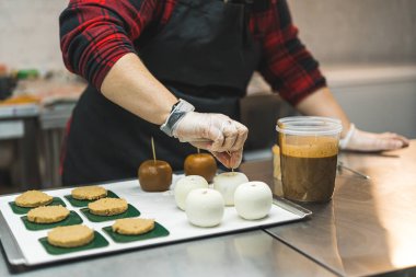 Baker, karamel kremasına batırmak için dört pastadan birini seçiyor. Orta boy. - Evet. Yüksek kalite fotoğraf