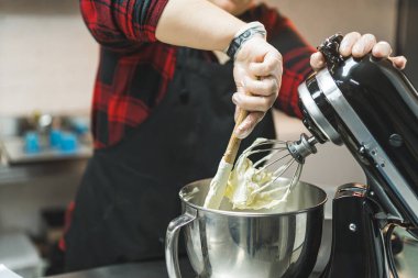 Fırın ekipmanları. Beyaz adam spatula ve kremalı pasta yapmak için ayakta karıştırıcı kullanıyor. Yüksek kalite fotoğraf