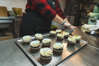 Fırın mutfağında tanınmayan biri renkli malzemelerle kek süslüyor. Küçük işletme konsepti. Yüksek kalite fotoğraf