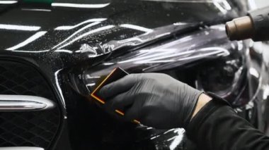 Profesyonel bir araba lambası boyasının yakın çekimi. Uzman, sünger ve kurutma makinesi kullanıyor. Son derece yakın çekim. Yüksek kalite 4k görüntü