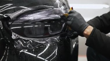 Loş bir arabanın ön lambasını bitirmenin ön çekimi. Her şey araba galerisinde özel bir yerde olur. Yakın çekim. Yüksek kalite 4k görüntü