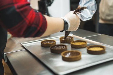 Pasta poşetinden çikolata kremalı turta yapan bir fırıncının yan görüntüsü. Ön planda bulanıklık. Yüksek kalite fotoğraf