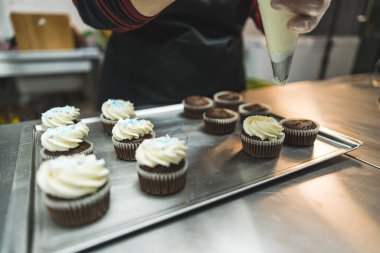 adding whipped cream to the chocolate cupcakes, bakery, dessert concept. High quality photo