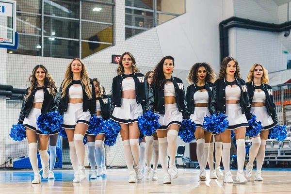 A group of cheerleaders in mini-skirts and knee-highs holding pom-poms showing team spirit.