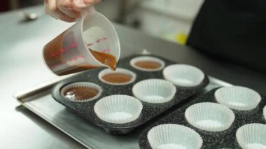 Chocolate cupcake batter. Unrecognizable caucasian pastry chef pouring batter into paper muffin mould in muffin liner. High quality 4k footage