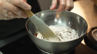 Melting chocolate chips. Dark chocolate chips melted with heavy cream in stainless steel bowl with a spatula. Indoor shot. High quality 4k footage