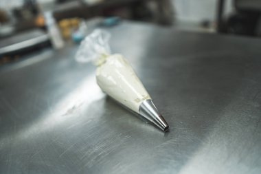 view of white glazing for gingerbread, brownies and cakes in a pastry bag on a kitchen table, cake decorating tool. High quality photo