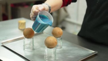Pastry decorating. Unconventional icing with blue coloring. Pralines and sweets. Blurred pastry chef in the background. High quality 4k footage