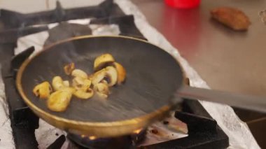 Chef preparing a flambe meat dish at gas stove in a restaurant kitchen. Closeup shot of tenderloin with mushroom dish. High quality 4k footage