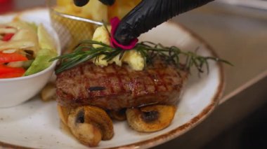 Top view of a striploin steak on mushrooms with salad and fries on side. Plate with meat dish on wooden table. High quality 4k footage